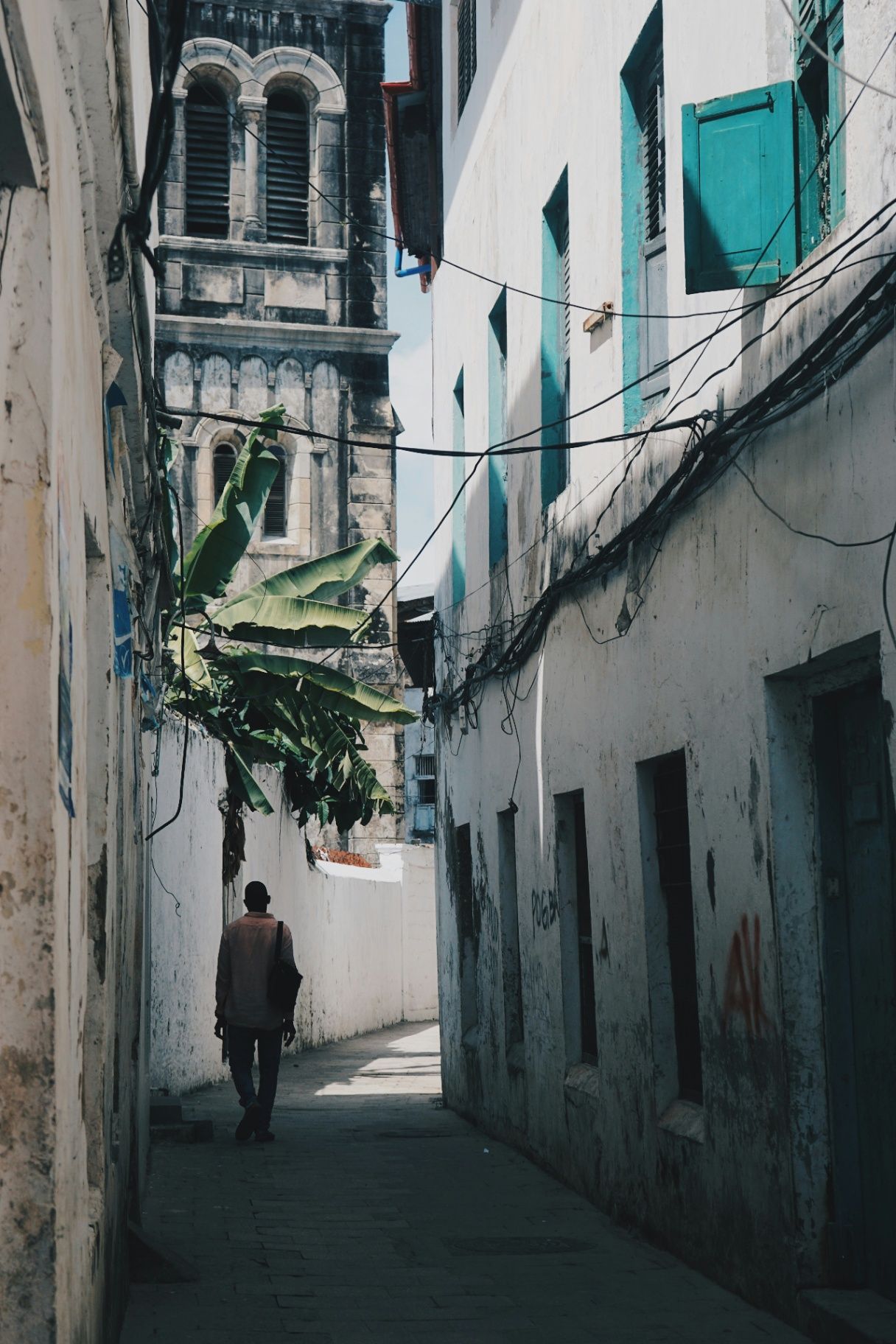 Stone Town alley framed by whitewashed buildings and a historic tower
